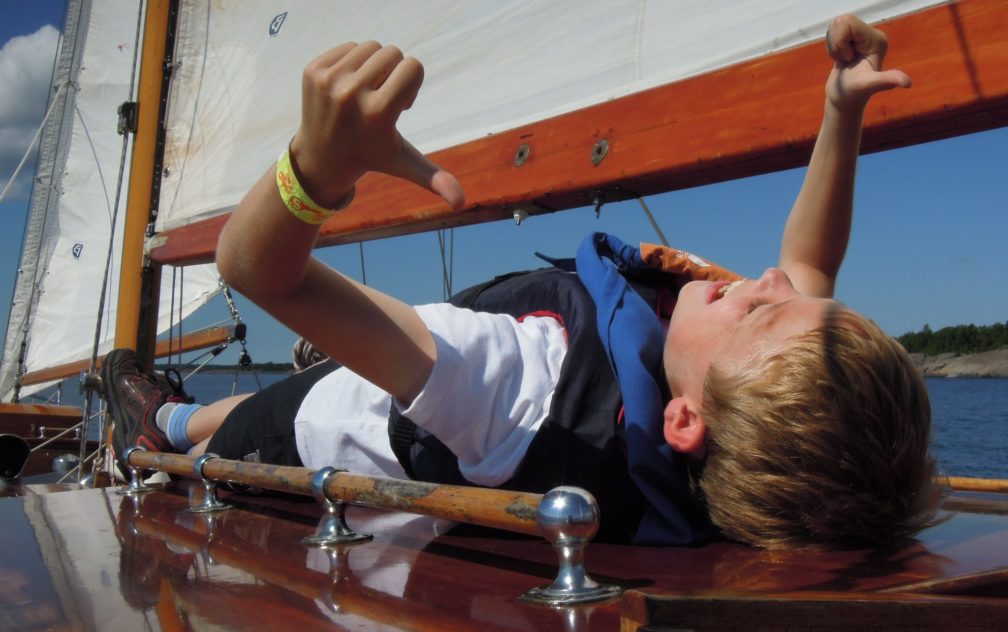 Glad pojke på segelbåt